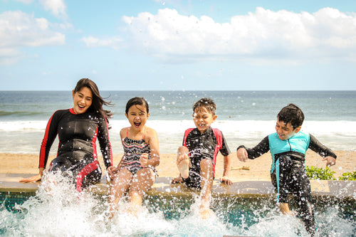 mom with children kicking feet in water